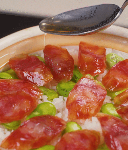 大米出現(xiàn)小孔時開蓋放香腸，往鍋邊淋入少許油，再燜煮8~10分鐘左右。